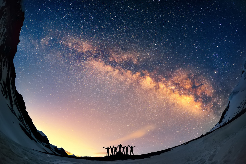Eine Gruppe Menschen vor dem mystischen Sternenhimmel mit untergehender Sonne