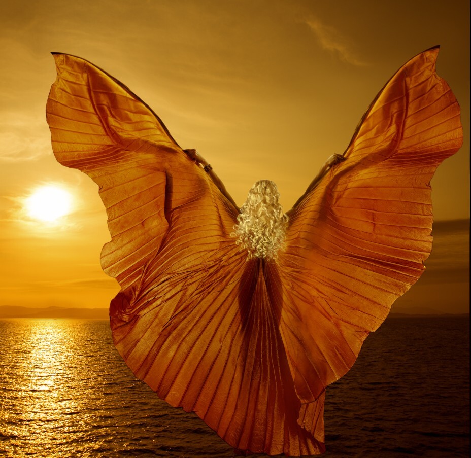 Frau mit flügelartigem Kleid vor Sonne