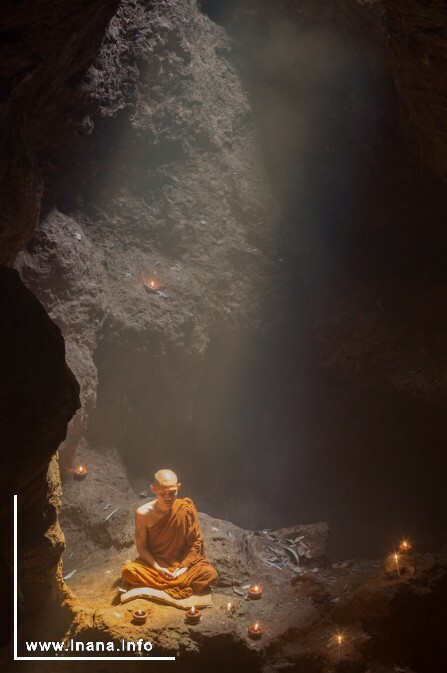 Buddhistischer Mönch mit Kerzen in einer Höhle meditierend