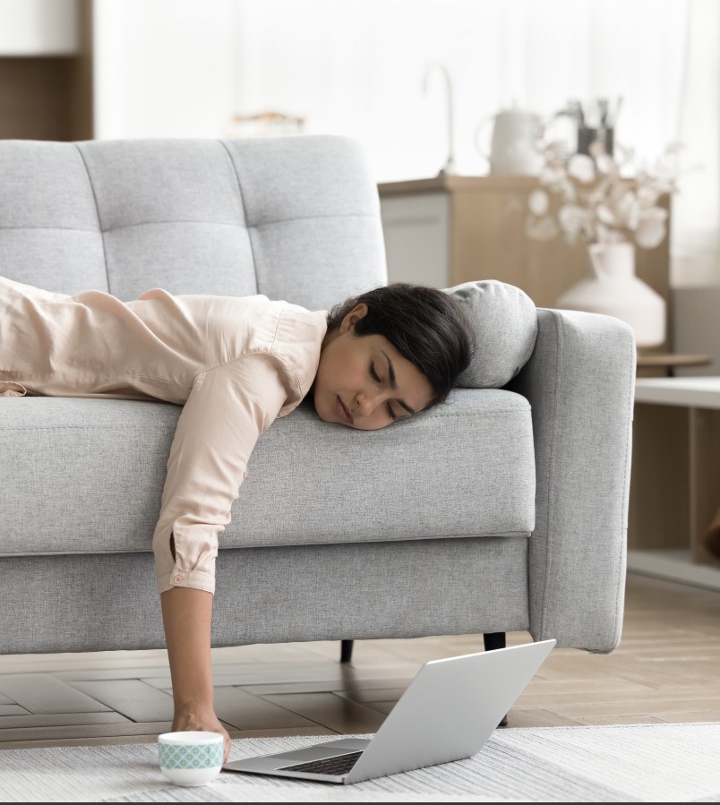 Frau liegt matt auf dem Sofa
