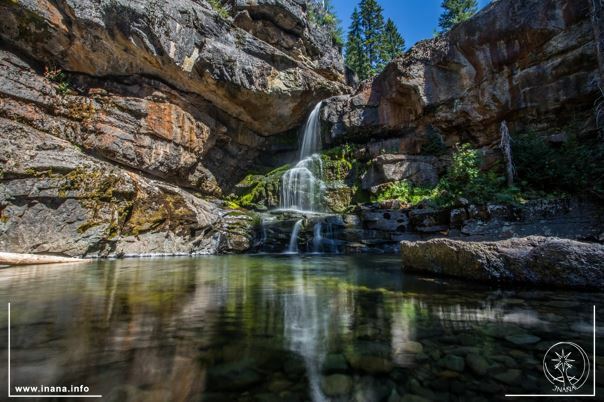 kleiner Wasserfall zwischen Felsen in einen See