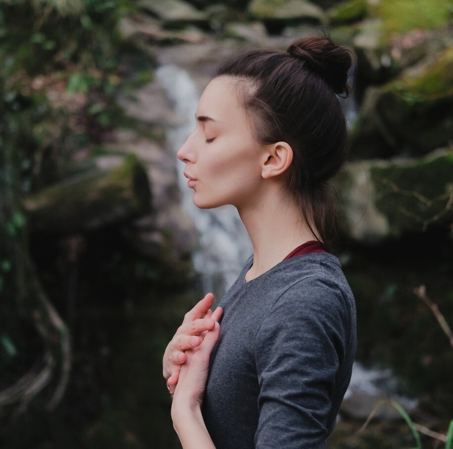 Frau in der Natur atmet in ihre Mitte