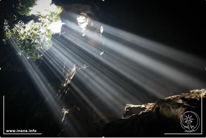 Lichtstrahlen fallen von oben in eine Höhle
